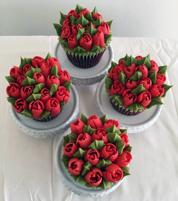 Red velvet cupcakes decorated with red buttercream flowers and leaves