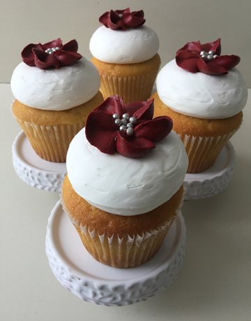 Vanilla cupcakes, topped with vanilla buttercream and decorated with red buttercream flowers with silver edible pearl centers