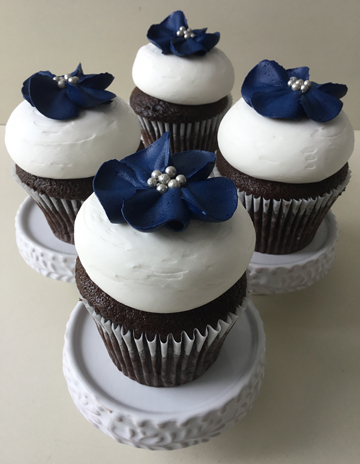 Vanilla cupcakes, topped with vanilla buttercream and decorated with blue buttercream flowers with silver edible pearl centers