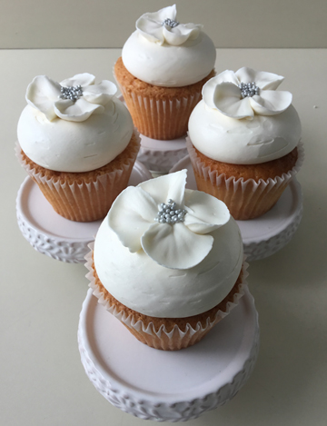Vanilla cupcakes, topped with vanilla buttercream and decorated with white blossom buttercream flowers with silver nonpareil centers