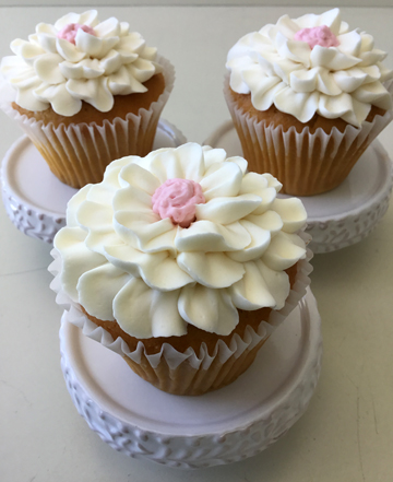Vanilla cupcakes, deocorated with white vanilla buttercream flowers with pink centers