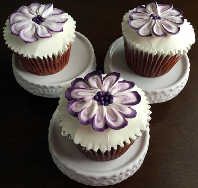 Red velvet cupcakes, filled with cream cheese icing, iced with vanilla buttercream and decorated with purple and white buttercream flowers delivered at Acorn Meadows in Thomasville PA