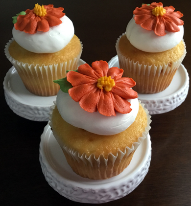 Yellow cupcakes filled with raspberry filling, iced with vanilla buttercream and decorated with burnt orange buttercream flowers delivered at Acorn Meadows in Thomasville PA