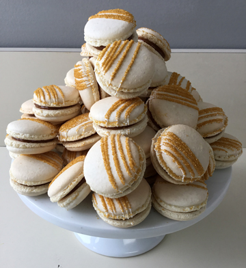 Gold French macarons filled with dulce de leche and decorated with gold sanding sugar stripes