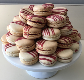 French macarons with raspberry filling, drizzled with burgundy chocolate stripes