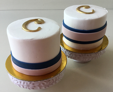 2 Inch round mini wedding cakes, iced in vanilla buttercream and decorated with fondant ribbons and gold initials